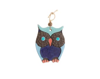 May include: A blue and brown ceramic owl ornament with turquoise eyes. The owl has a string attached to the top for hanging.