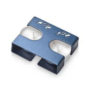 May include: A blue metal candle holder with two white tea lights. The holder has the word "Peace" cut out in the metal.