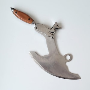 Può includere: Un coltello mezzaluna in acciaio inossidabile con manico in legno. Il coltello presenta un design decorativo a forma di volpe e una lama curva, ideale per tritare erbe e verdure. Il manico è marrone con tre rivetti.