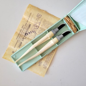 May include: A set of two craft knives with cream-colored handles and black blades, housed in a light green plastic case. The set includes a vintage paper document with Russian text titled "НАБОР ДЛЯ ИНКРУСТАЦИИ" and a small piece of brown paper.