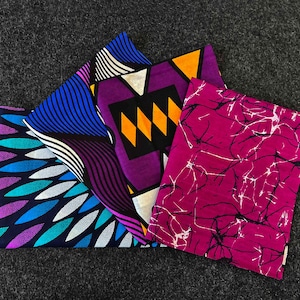 Op de afbeelding: Vier vierkante stukken stof met verschillende patronen. Een vierkant is blauw en wit met een bladpatroon, een is paars en zwart met een geometrisch patroon, een is paars en geel met een ruitpatroon en een is roze met een wit marmerpatroon.