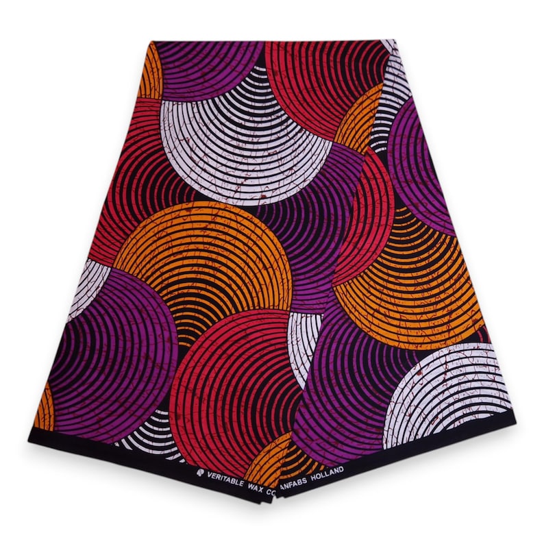 May include: A vibrant fabric with a repeating circular pattern in shades of orange, red, purple, and white on a black background. The fabric has a bold, graphic design, with the text "VERITABLE WAX CO ANFABS HOLLAND" printed along the bottom edge.