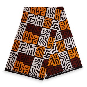 Puede incluir: Tela doblada con un patrón geométrico en naranja, blanco, marrón y negro. La tela tiene el texto "VERITABLE WAX COTTON AFRICANFABS HOLLAND" y "GUARANTEED WAX COTTON AFRICANFABS HOLLAND" impreso en los bordes. El diseño presenta formas abstractas repetidas.