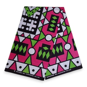 Op de afbeelding: Een gevouwen stuk stof met een geometrisch patroon in roze, groen, zwart en wit. De stof heeft de tekst "VERITABLE WAX AFRICANFABS HOLLAND" en "GUARANTEED WAX AFRICANFABS HOLLAND" erop gedrukt.
