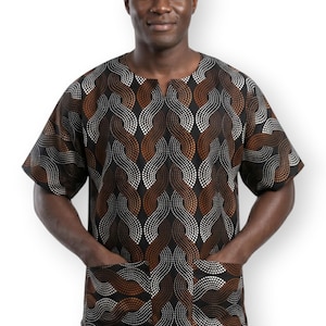 Op de afbeelding: Een shirt met korte mouwen en een gestippeld golfpatroon in zwart, bruin en wit. Het kledingstuk heeft een ronde halslijn met een kleine split in het midden en twee grote vierkante opgestikte zakken aan de voorzijde van de stof.