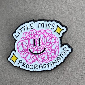 Peut inclure: Une broche en émail blanc avec une bordure noire représentant un cercle rose gribouillé avec un visage souriant noir. Le texte LITTLE MISS PROCRASTINATOR est écrit en lettres capitales noires, accompagné de deux petites étoiles jaunes à quatre branches.