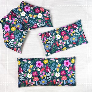 May include: Several rectangular and curved fabric items with a dark green background. The fabric is patterned with colorful flowers, butterflies, and mushrooms. The items appear to be filled with a soft material.