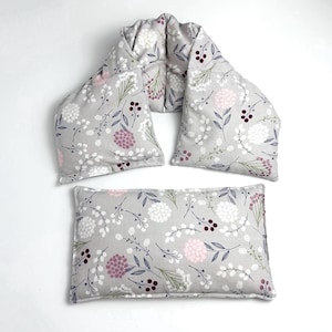 May include: A set of three gray fabric neck and shoulder heating pads with a floral pattern in shades of white, pink, and burgundy.