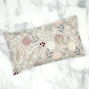 A grey rectangular rice bag pillow with a floral pattern. The pattern features white, pink, and burgundy flowers and leaves on a light grey background.