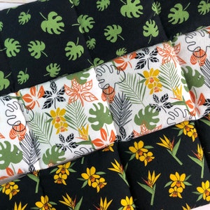 May include: A set of six black fabric squares with different tropical leaf and flower patterns. The squares are sewn together to create a larger piece of fabric.