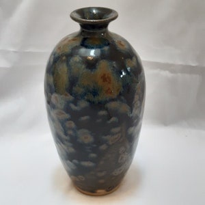 May include: A dark blue ceramic vase with a speckled glaze. The vase has a rounded body and a narrow neck.