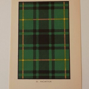 May include: A printed card displaying a green, black, yellow, and pink tartan pattern. The design is a grid of intersecting lines, with the name "MACARTHUR" and the number "50" printed at the bottom. The card has a cream-coloured border.