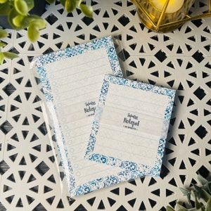 May include: Two blue and white patterned notepads with the text "Infinitive Notepad - 50 Sheets -" on the front.