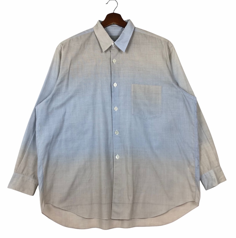 Op de afbeelding: Een lang mouw ombre overhemd met knopen, met een gradi&euml;nt van lichtblauw naar beige. Het overhemd heeft een enkele borstzak en een klassieke kraag.