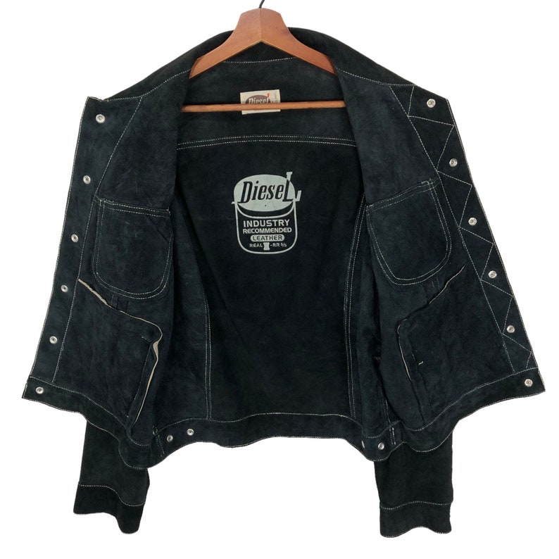 Puede incluir: Chaqueta de ante negro con una etiqueta Diesel en el interior. La etiqueta dice "Industry Recommended Leather Real 100%".