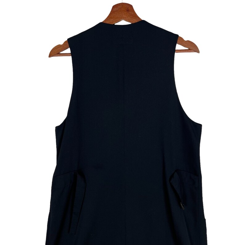 May include: A black sleeveless vest with a high neckline and two pockets on the sides.
