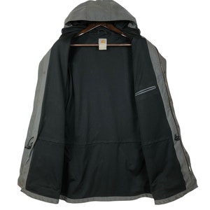 May include: A gray hooded jacket with a black mesh lining. The jacket has a zipper closure and two pockets on the front. The jacket is unbuttoned and the hood is down.