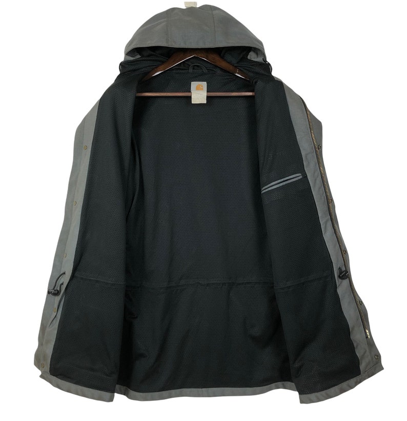 May include: A gray hooded jacket with a black mesh lining. The jacket has a zipper closure and two pockets on the front. The jacket is unbuttoned and the hood is down.