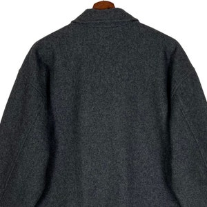 May include: A dark gray wool jacket with a collar and long sleeves.