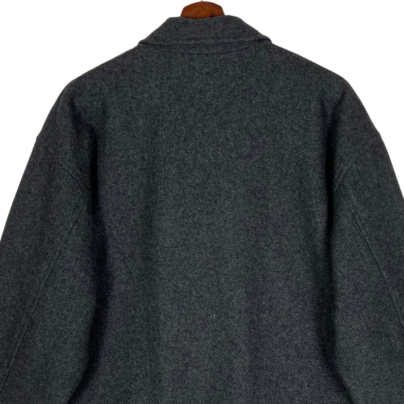 May include: A dark gray wool jacket with a collar and long sleeves.