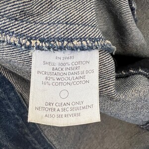 Pode incluir: Close-up de uma etiqueta de roupa branca com texto preto. A etiqueta diz "RN 29685 SHELL: 100% COTTON BACK INSERT INCRUSTATION DANS LE DOS 82% WOOL/LAINE 18% COTTON/COTON DRY CLEAN ONLY NETTOYER A SEC SEULEMENT ALSO SEE REVERSE."