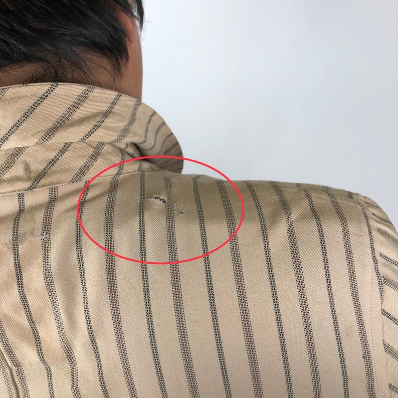 K&ouml;nnte beinhalten: Ein beige gestreiftes Hemd mit einem kleinen Loch in der Schulterpartie.