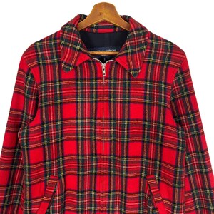 May include: Red and black plaid jacket with a zipper closure. The jacket has a collar and two pockets. The label on the jacket reads "Comme des Gar&ccedil;ons."