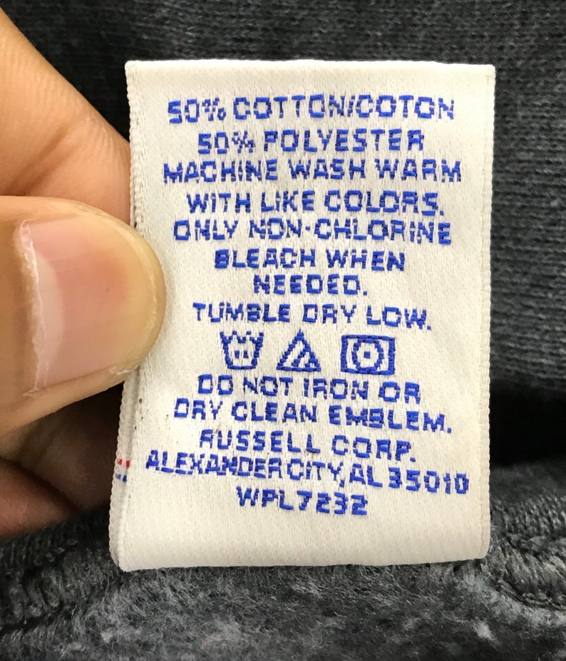 May include: White care label with blue text. 50% Cotton/Cotton 50% Polyester. Machine wash warm with like colors. Only non-chlorine bleach when needed. Tumble dry low. Do not iron or dry clean emblem. Russell Corp. Alexander City, AL 35010 WPL 7232.