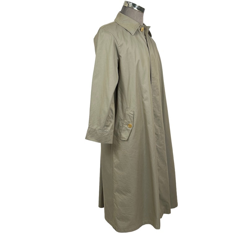 May include: A long, light brown trench coat with a button-up collar and a single pocket on the left side.