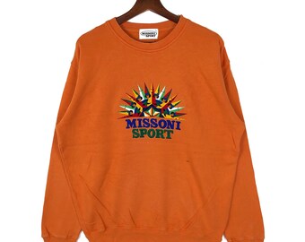 Puede incluir: Sudadera naranja con un logotipo colorido de Missoni Sport que presenta un diseño de sol radiante.