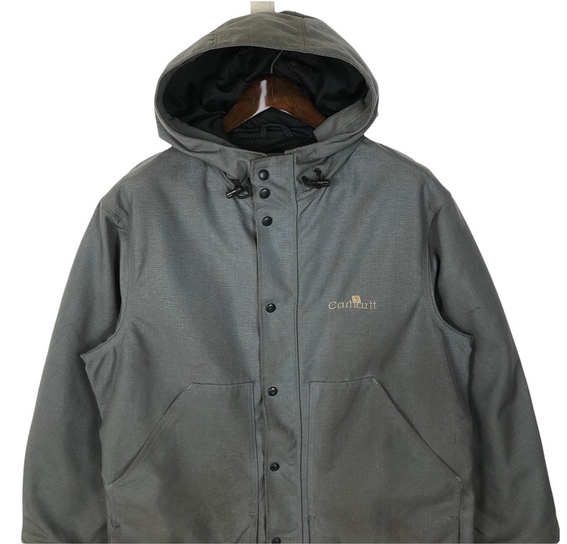May include: A gray Carhartt hooded jacket with a button front closure and a logo on the chest.