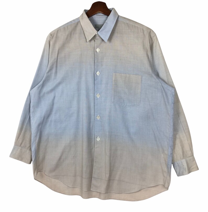 Op de afbeelding: Een lichtblauw overhemd met lange mouwen en knopen, met een kleurverloop naar wit. Het overhemd heeft een borstzak en een knoopsluiting.