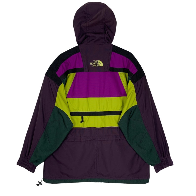 May include: A purple, green, and yellow color-blocked ski jacket with a hood. The jacket has a zipper closure and a logo that reads "The North Face".