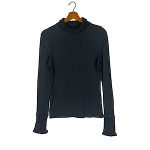 Op de afbeelding: Een zwarte longsleeve trui met een hoge hals en geribbelde manchetten.