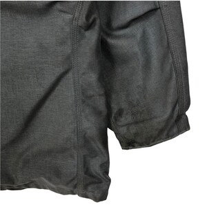 May include: A dark gray jacket with a zipper closure and a quilted design. The jacket has a seam down the side and a ribbed cuff.