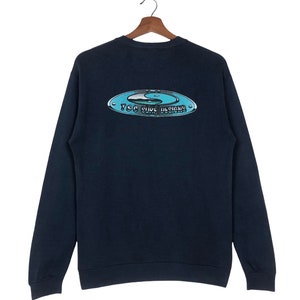 Pu&ograve; includere: Una felpa blu navy con una grafica bianca e blu di un simbolo yin yang e il testo "TSC Surf Designs".