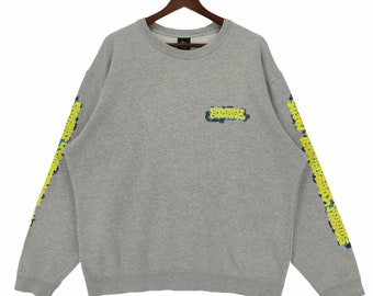 May include: Gray sweatshirt with a yellow and blue graphic on the front that says "Sugarshock" and yellow and blue graphics on the sleeves that say "Sugarshock".