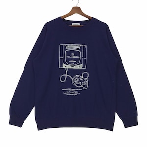Könnte beinhalten: Ein marineblaues Sweatshirt mit einer weißen Grafik einer Sega Saturn Konsole und eines Controllers. Der Text "SEGA SATURN represents a leap into the new age of entertainment. We launch a new step for SEGA. Let's go forward together." ist unter der Grafik aufgedruckt.