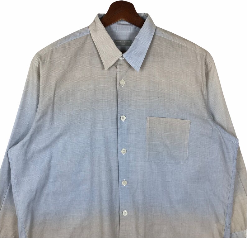 Op de afbeelding: Een lang mouw ombre overhemd met knopen, met een lichte blauwe tot beige gradi&euml;nt. Het overhemd heeft een borstzak en een knoopsluiting.