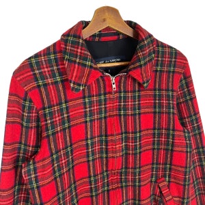 May include: Red, green, and yellow plaid jacket with a zipper closure. The jacket has a black label with the text "COMME des GARCONS" on the collar.