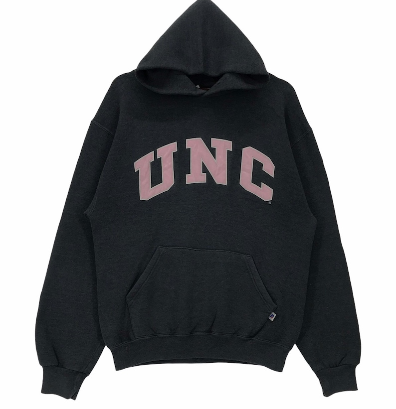 May include: Black hooded sweatshirt with a large pink UNC logo on the front. The sweatshirt has a kangaroo pocket and a drawstring hood.