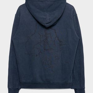 May include: A dark navy blue long-sleeve hooded sweatshirt featuring a subtle, darker-toned lightning bolt graphic pattern across the back. The hoodie includes a hood, ribbed cuffs, and a ribbed hem, showcasing a faded, worn-in fabric texture.