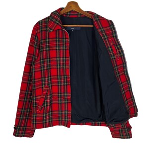 May include: A red and black plaid jacket with a zipper closure. The jacket has a black lining and a pocket on the left side.