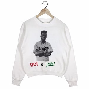 May include: White sweatshirt featuring a black and white image of a person wearing a baseball jersey with the word "Dodgers" on it. The text "get a job!" is printed in red, green, and black below the image.
