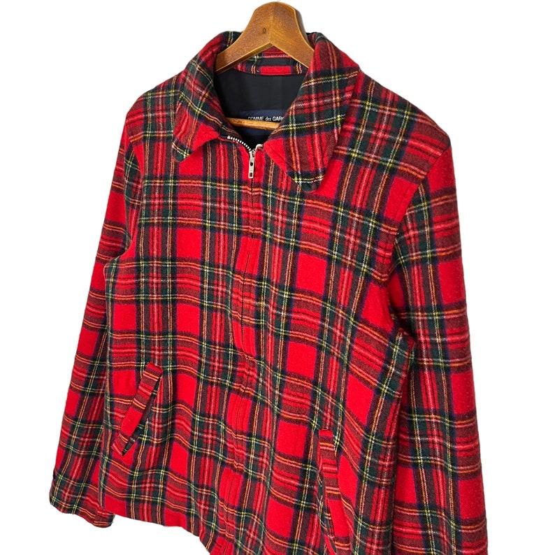 May include: Red and black plaid jacket with a zipper closure. The jacket has a collar and two pockets.