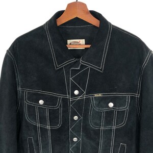 Puede incluir: Chaqueta de ante negro con costuras blancas y la marca Diesel. La chaqueta tiene cierre de botones y dos bolsillos de solapa.