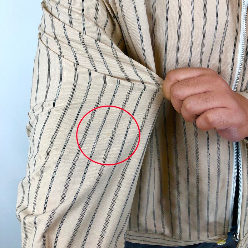 K&ouml;nnte beinhalten: Ein beige gestreiftes Hemd mit einem kleinen braunen Fleck auf dem &Auml;rmel.