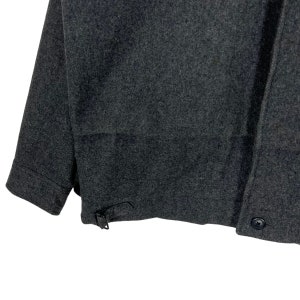 May include: A dark gray wool jacket with a button closure and a buckle strap on the side.