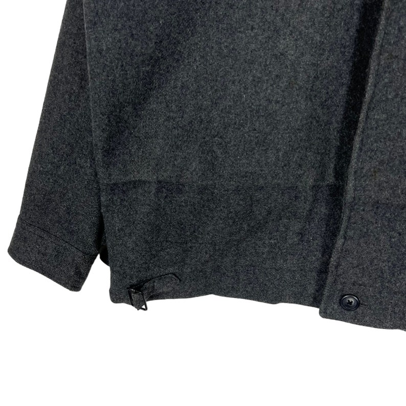 May include: A dark gray wool jacket with a button closure and a buckle strap on the side.