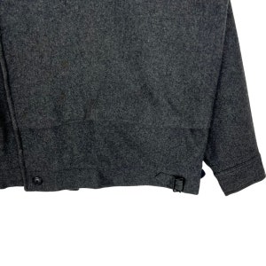 May include: A dark gray wool jacket with a button closure and a strap on the bottom.